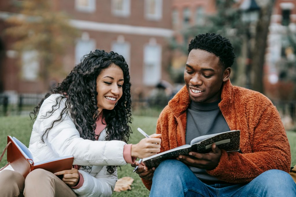 pexels photo 6147369 6147369 Happy college students studying together on a campus lawn, sharing ideas and writing notes.